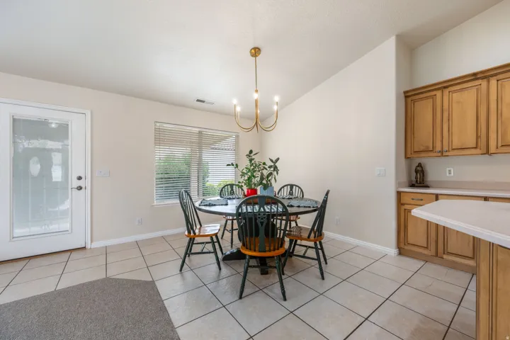 Tile flooring throughout, natural wood-finish cabinetry, light-colored countertops, and a full-light exterior door