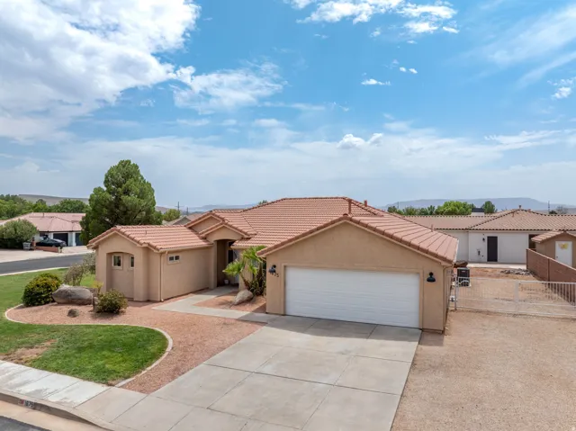 Southwestern-style residence featuring a clay tile roof, stucco exterior, and two-car garage with white paneled door