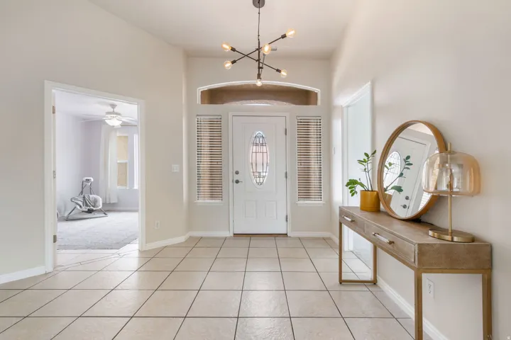 Tiled entryway featuring a decorative glass-paneled door, transom window, and two side windows with blinds