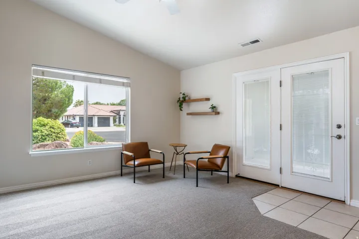 Bright, light-filled room with expansive windows overlooking the front landscape, neutral wall finishes, and tile flooring near the entry