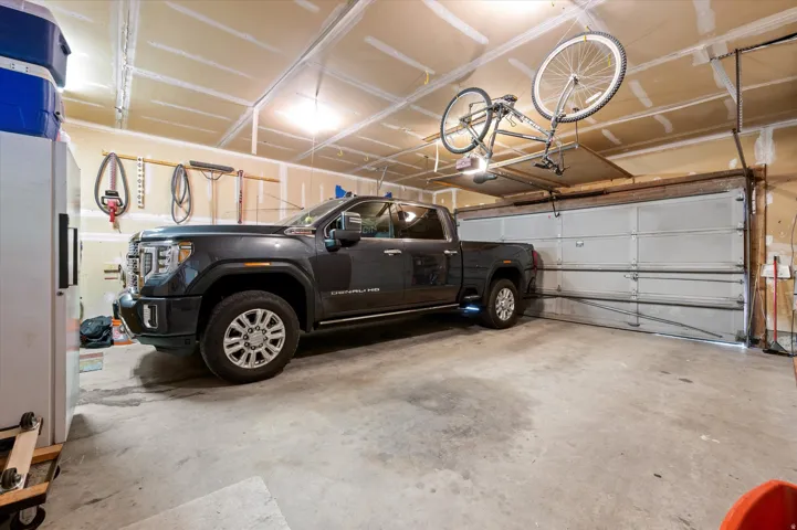 Attached garage with concrete flooring, overhead lighting, and exposed ceiling joists