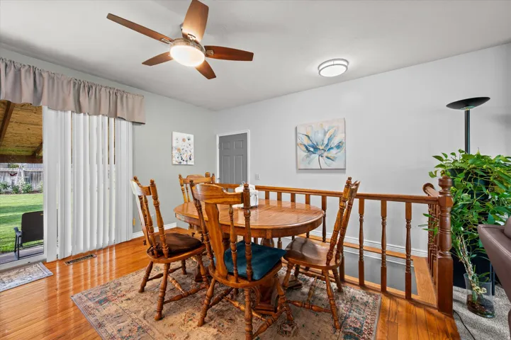 Elegant dining room showcasing warm wood-finish flooring, a round pedestal dining table with coordinating chairs, and abundant natural light from sliding glass doors