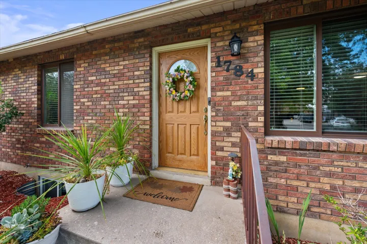 Brick exterior with a natural wood-finish entry door, dark-framed windows, and exterior light fixture