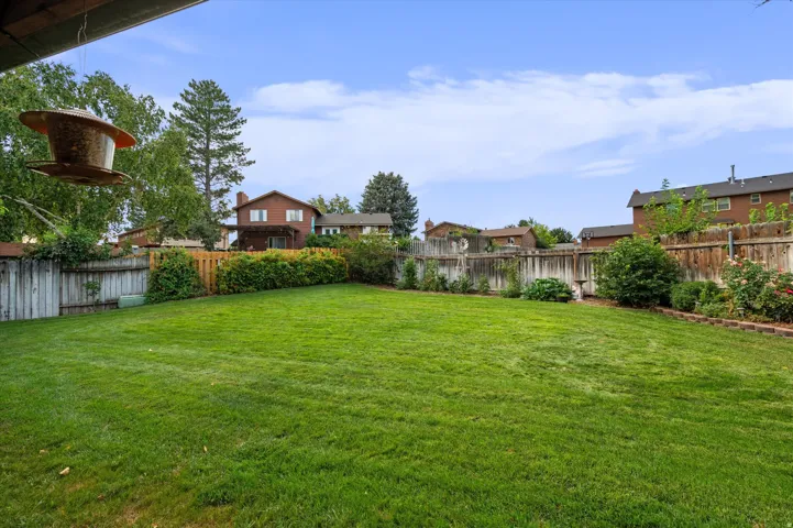 Expansive lawn bordered by a wood fence, mature landscaping, and established plantings