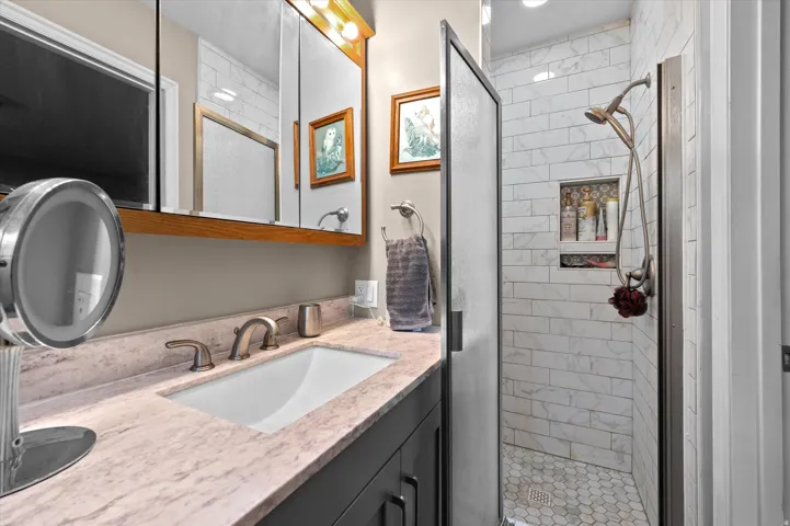 Master bathroom featuring a dual-sink vanity with marble-look countertop, undermount basin, and bronze-finish faucetry