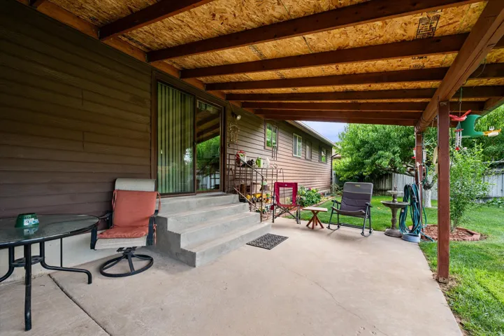 Covered concrete patio with exposed wood beam ceiling, siding exterior, and sliding glass door access