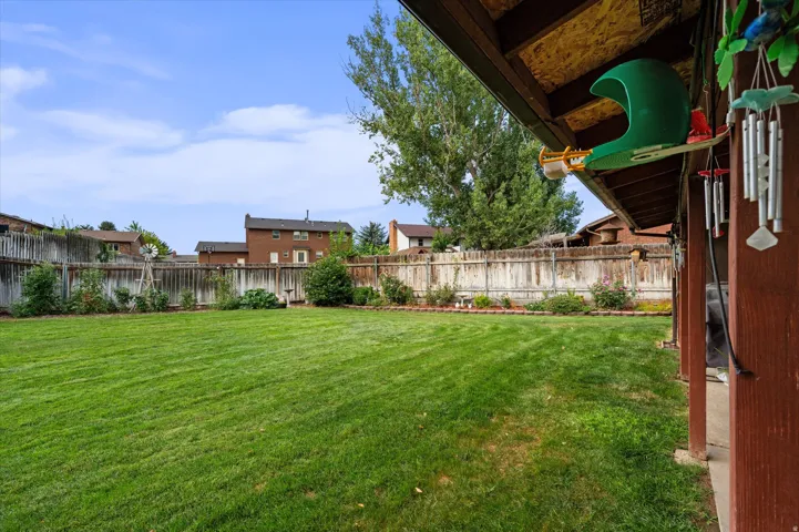 Expansive backyard featuring a generously proportioned manicured lawn, mature shade trees, and wooden privacy fencing