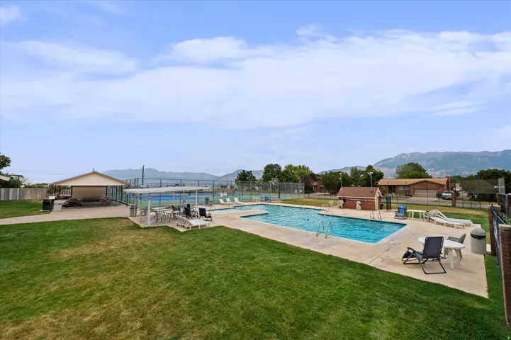 Expansive outdoor common area featuring a swimming pool, covered patio, tennis courts, and a separate covered pavilion