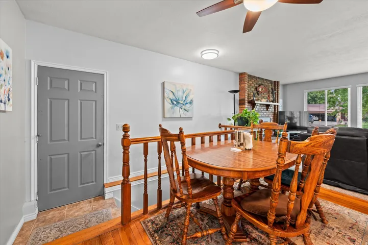 Dining room featuring a round wood-finish table, spindle-back chairs, and warm wood flooring accented with a patterned area rug