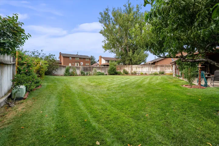 Expansive lawn area with a perimeter fence, mature trees, and landscaping