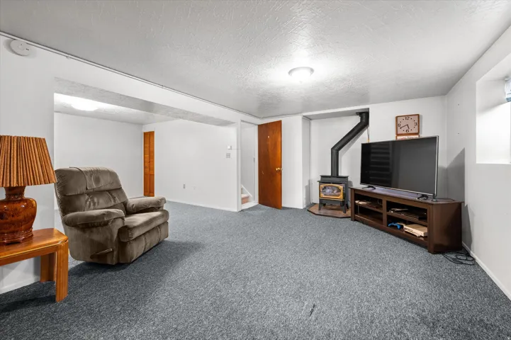 Spacious basement recreation room featuring wall-to-wall carpeting, recessed ceiling lighting, and a built-in entertainment center with shelving