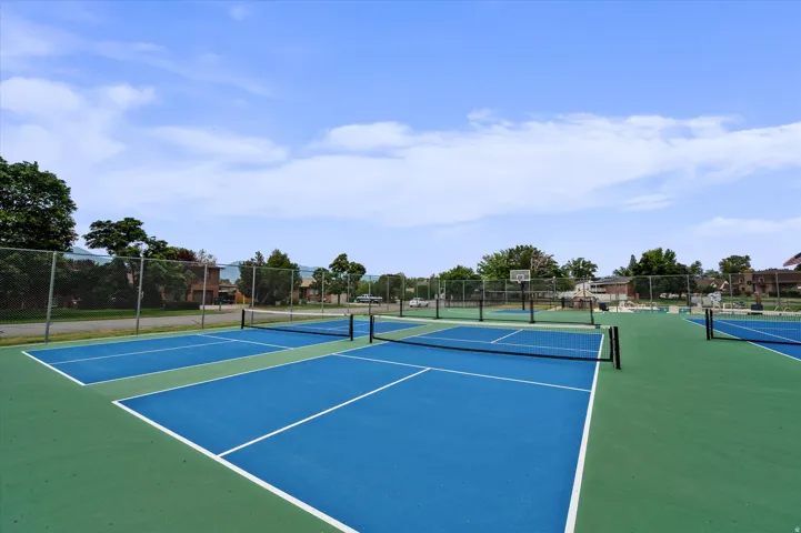 Multiple hard-surface courts with blue and green coloring, equipped with nets and fencing