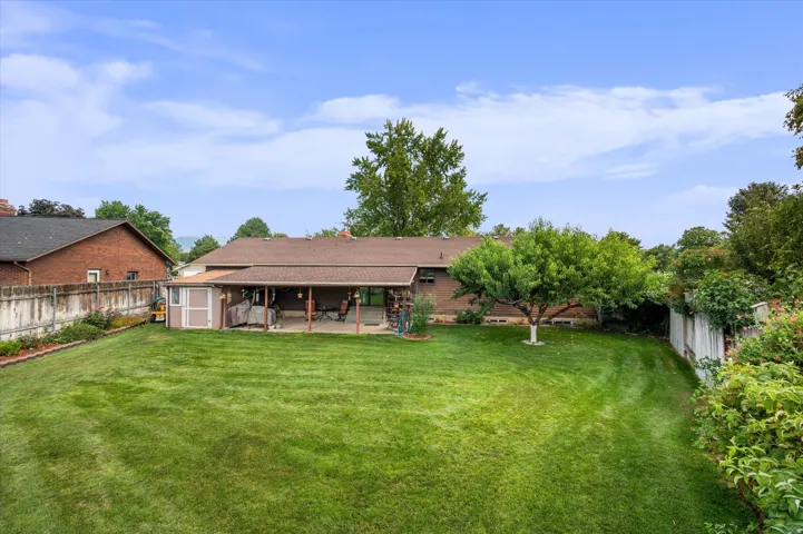 Expansive grass lawn with mature trees and a privacy fence