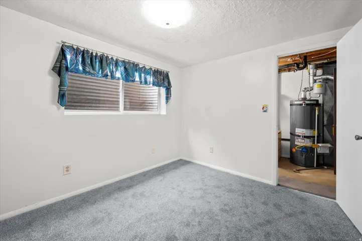 Versatile bedroom featuring neutral wall finishes, carpet flooring, and abundant natural light from a high window with privacy treatments
