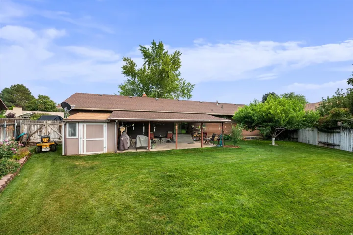 Expansive backyard featuring a manicured lawn, mature shade trees, and a covered pavilion structure with open sides—ideal for outdoor entertaining and recreation