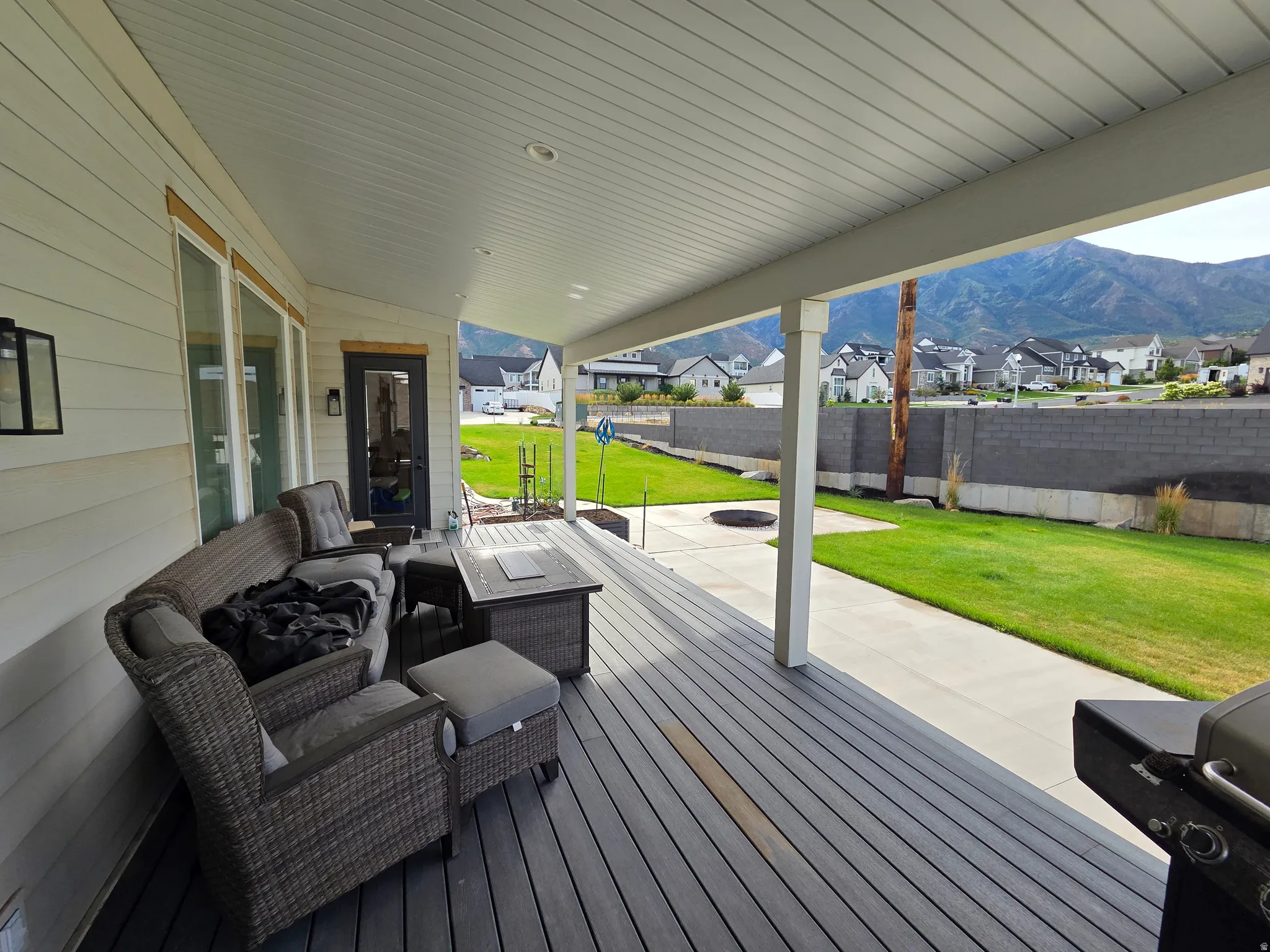 Covered porch with composite decking, recessed lighting, and direct access to a landscaped yard with a concrete pathway