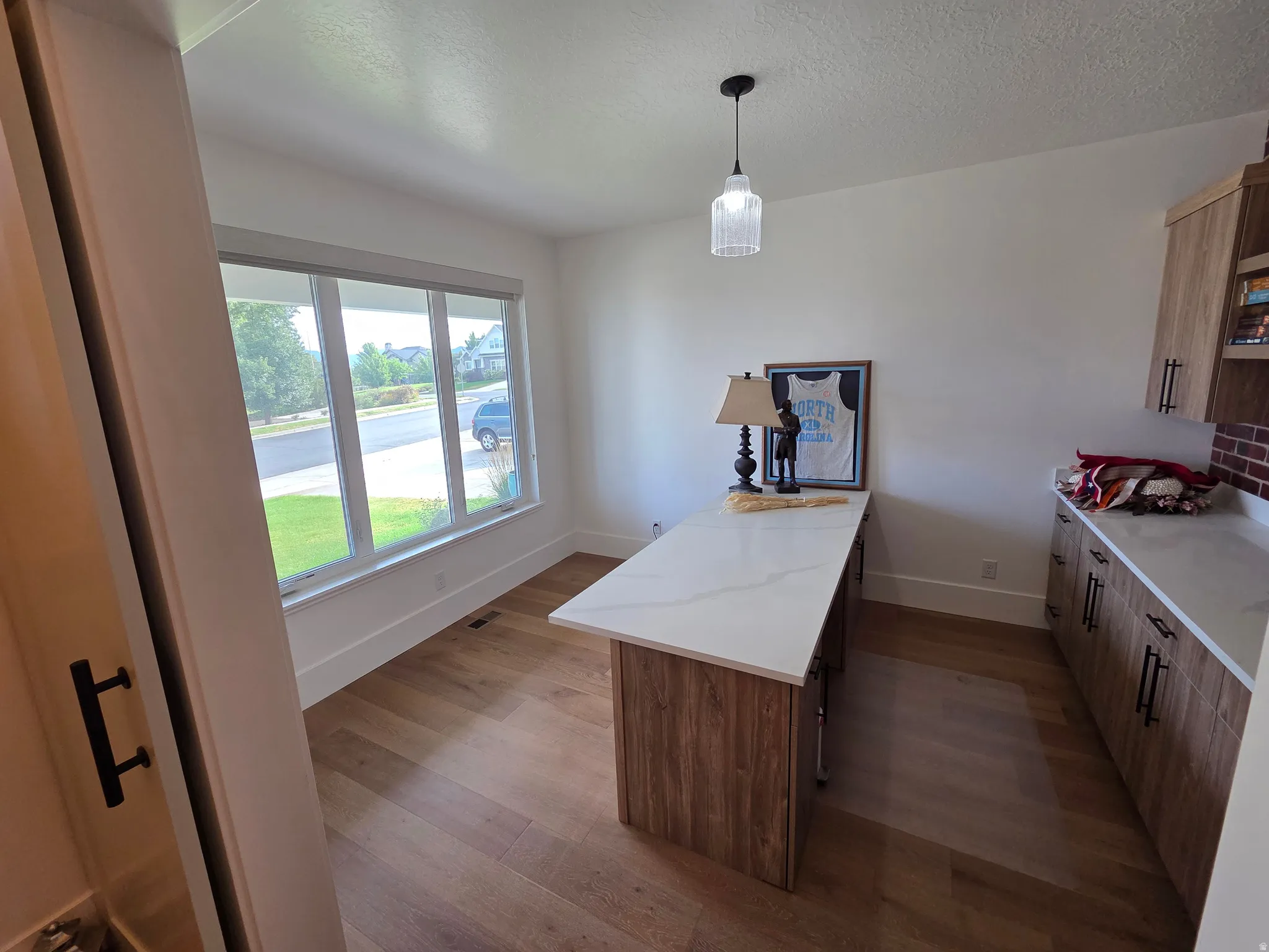 Modern kitchen featuring wood-finish cabinetry, white quartz countertops, and a substantial island with wood-tone base