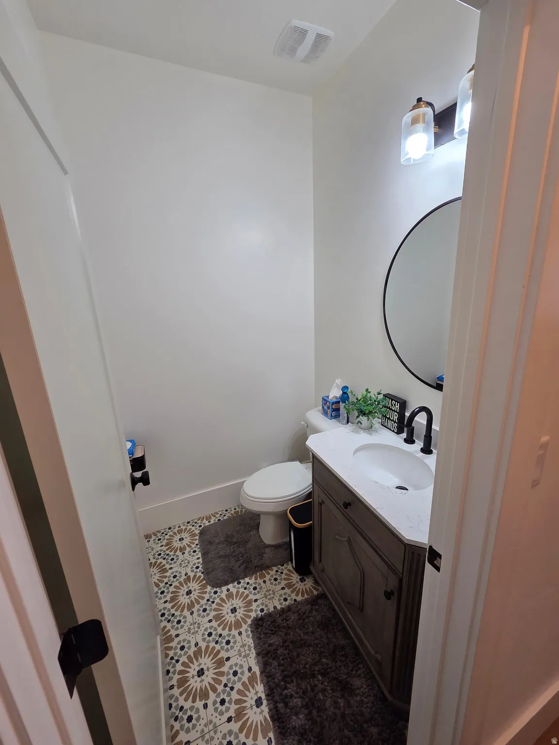 Modern half bath featuring a wood-finish vanity with an integrated rectangular sink, quartz countertop, and matte black faucet