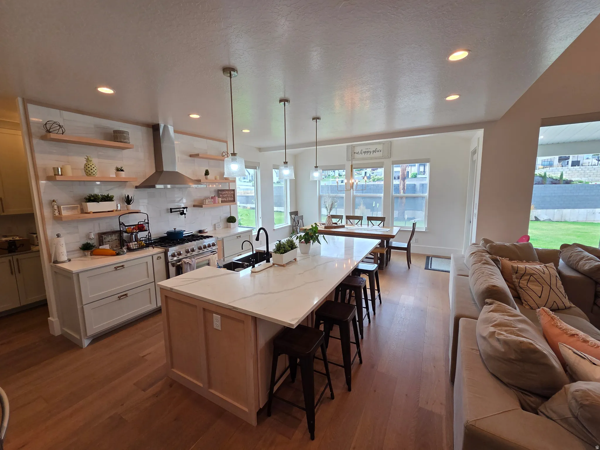Open-concept kitchen and dining area featuring a large center island with seating, stainless steel appliances, and wood-finish flooring