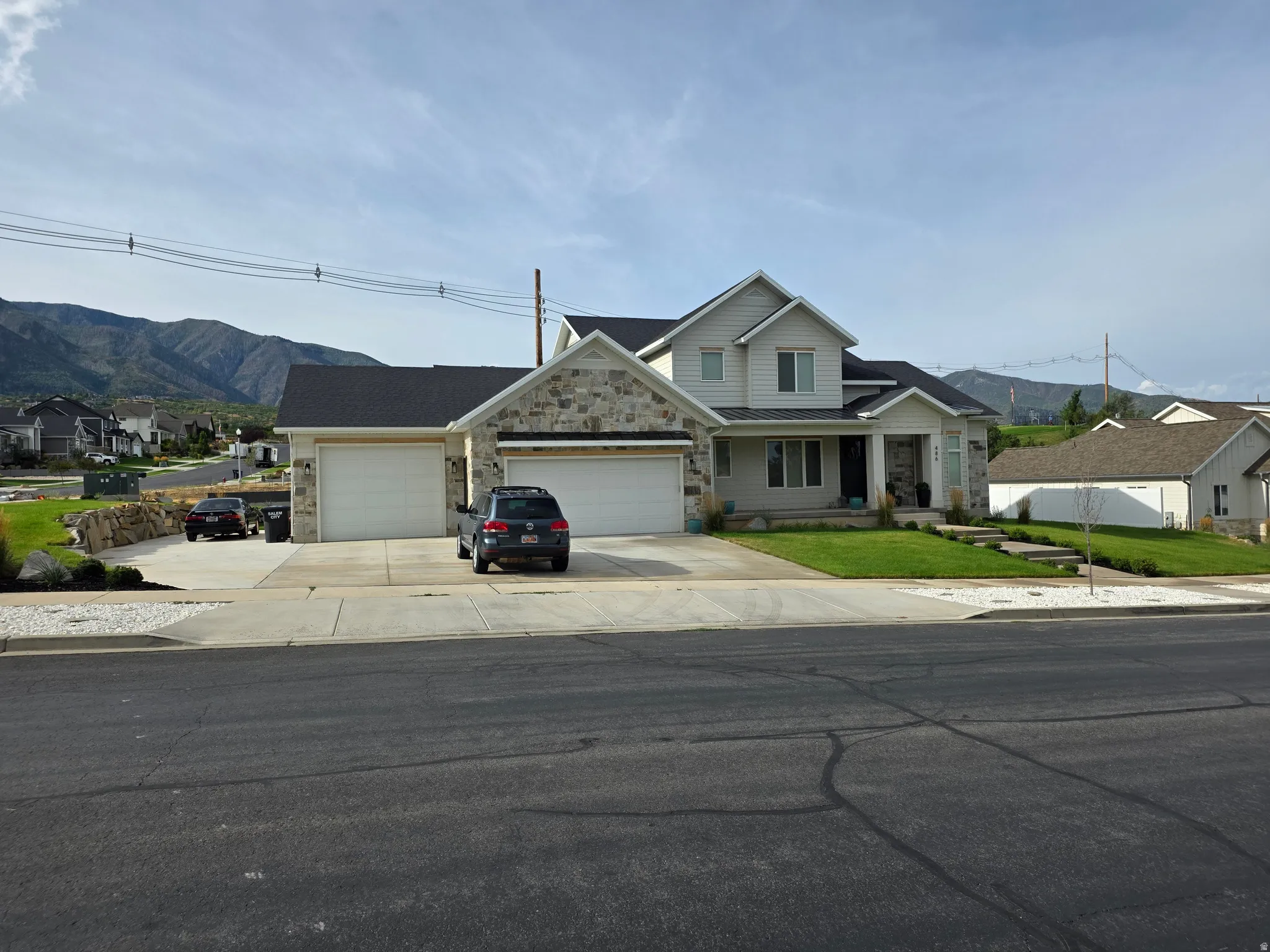Stone and siding exterior with a multi-car driveway, attached garage, and mountain backdrop