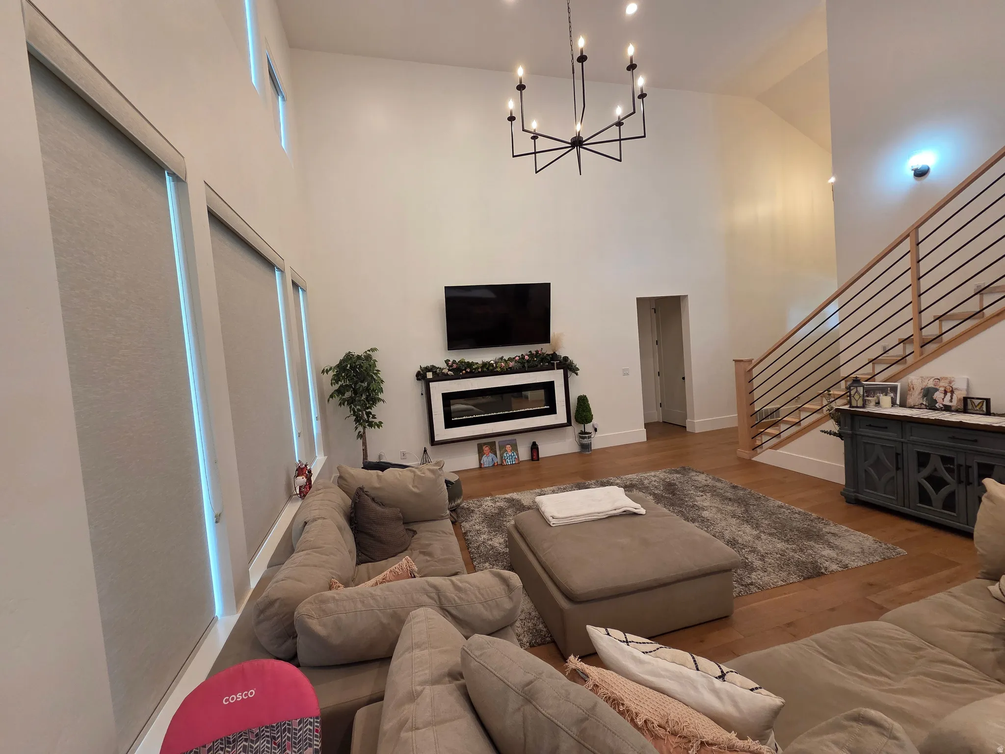 Open-concept living area featuring soaring ceilings with skylights, a modern linear chandelier, and hardwood flooring throughout