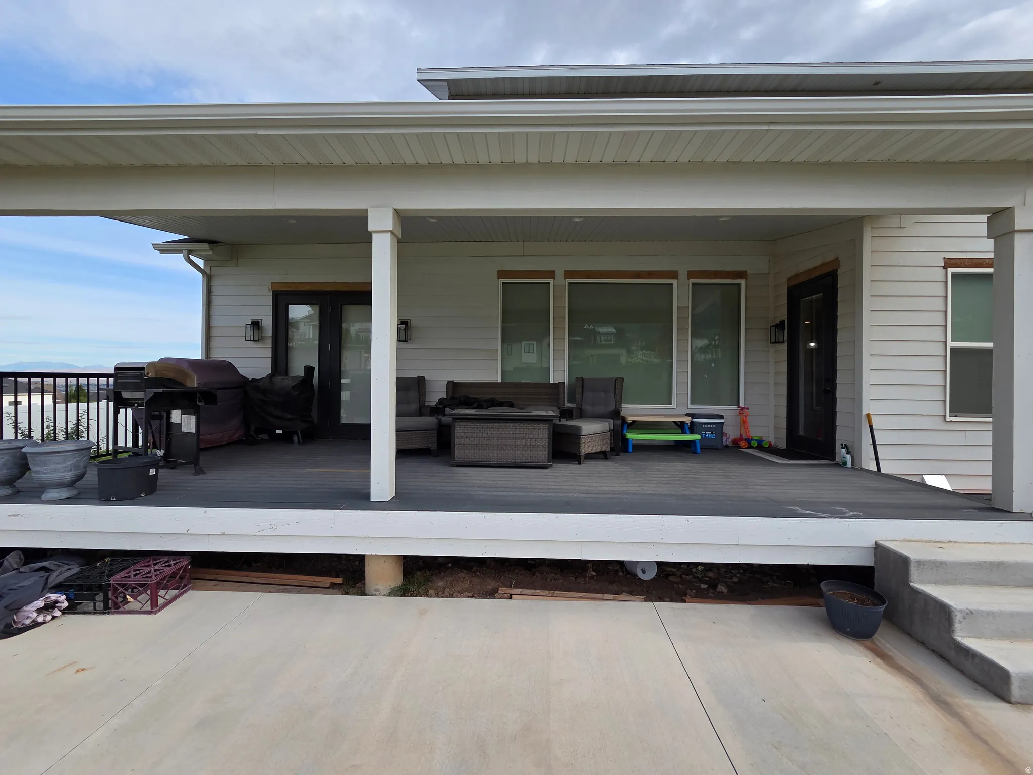 Expansive covered porch with composite decking, multiple support columns, and large multi-pane glass doors providing access to the residence