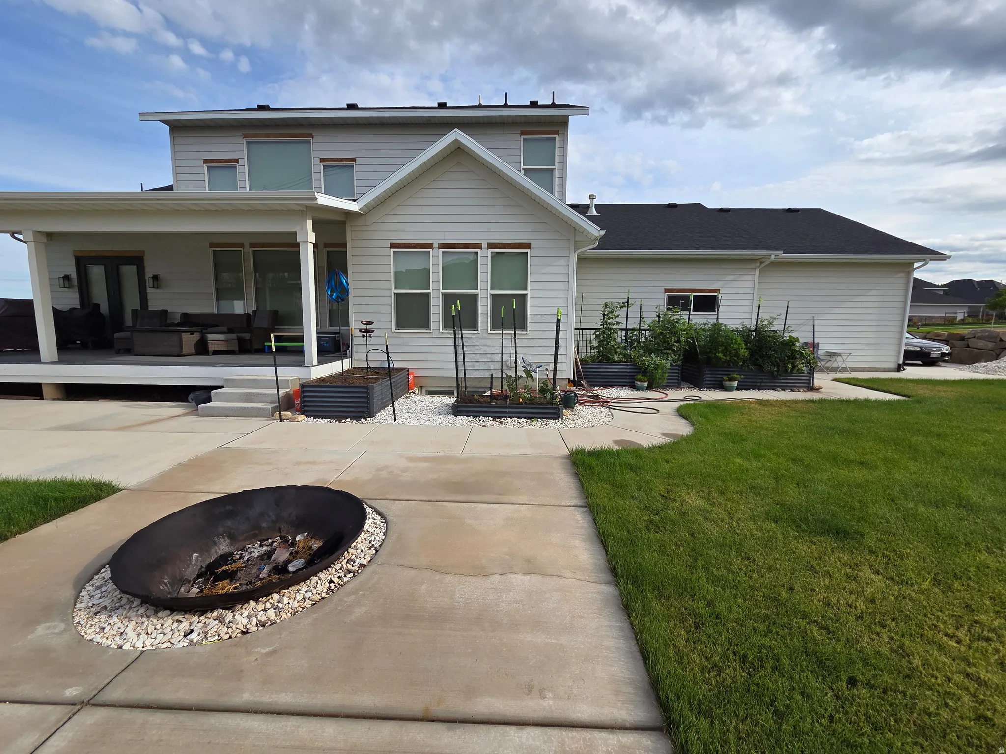 Modern farmhouse exterior with covered front porch, two-story design featuring gabled roofline, and mature landscaping