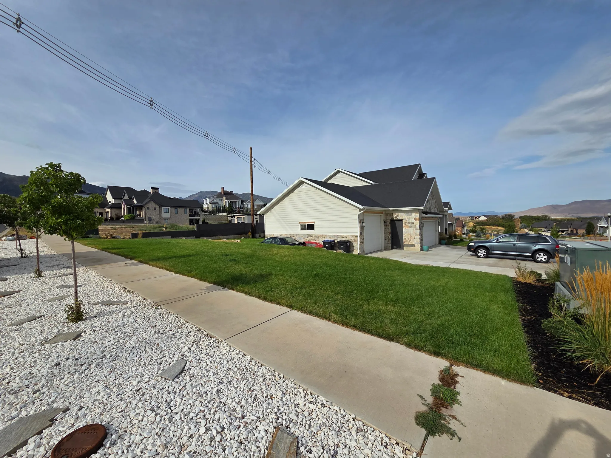 Two-car garage with overhead doors, stone and siding exterior, concrete driveway, and manicured lawn