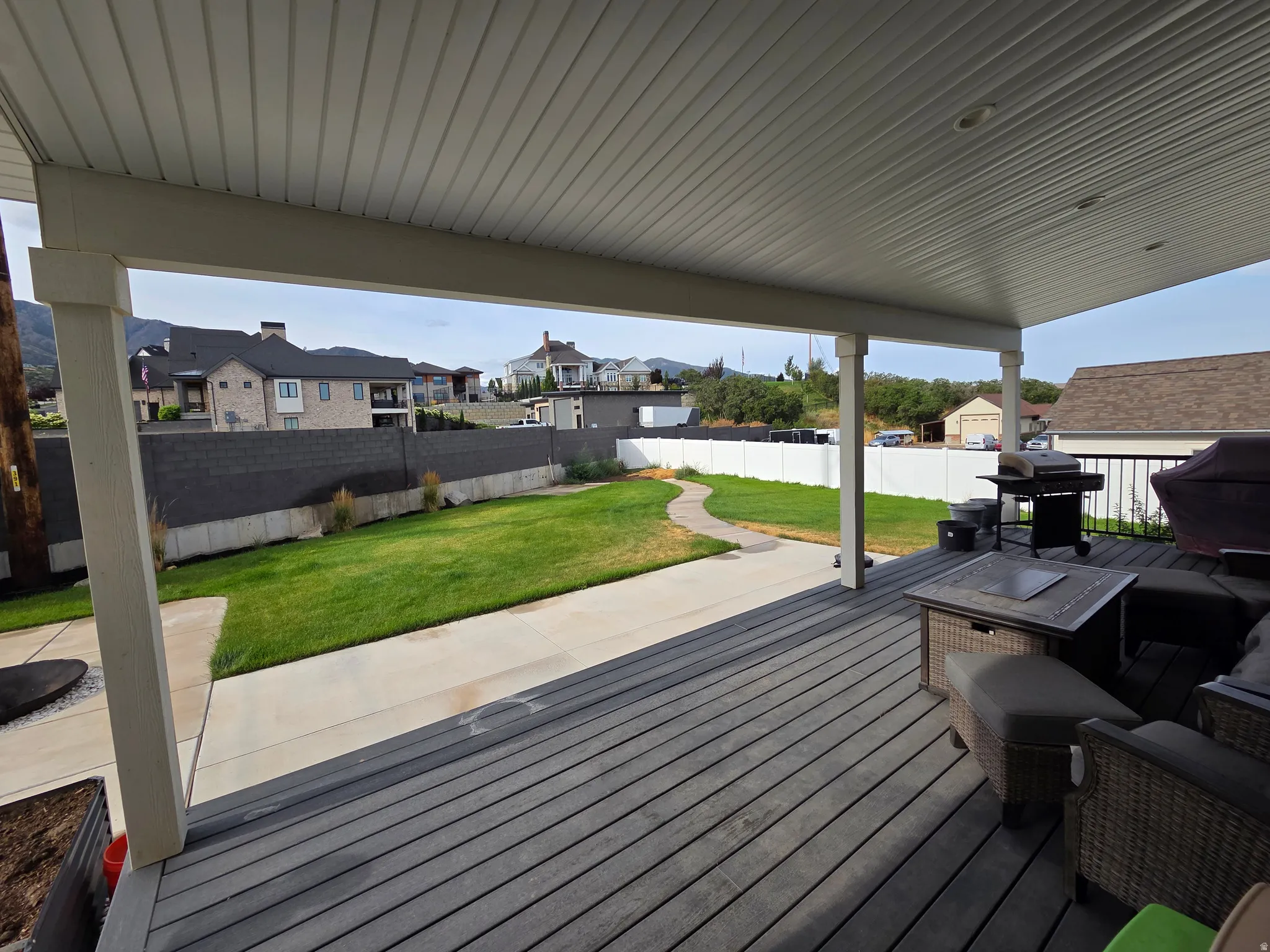 Spacious composite deck with composite decking and metal railings overlooking a level lawn with mature landscaping