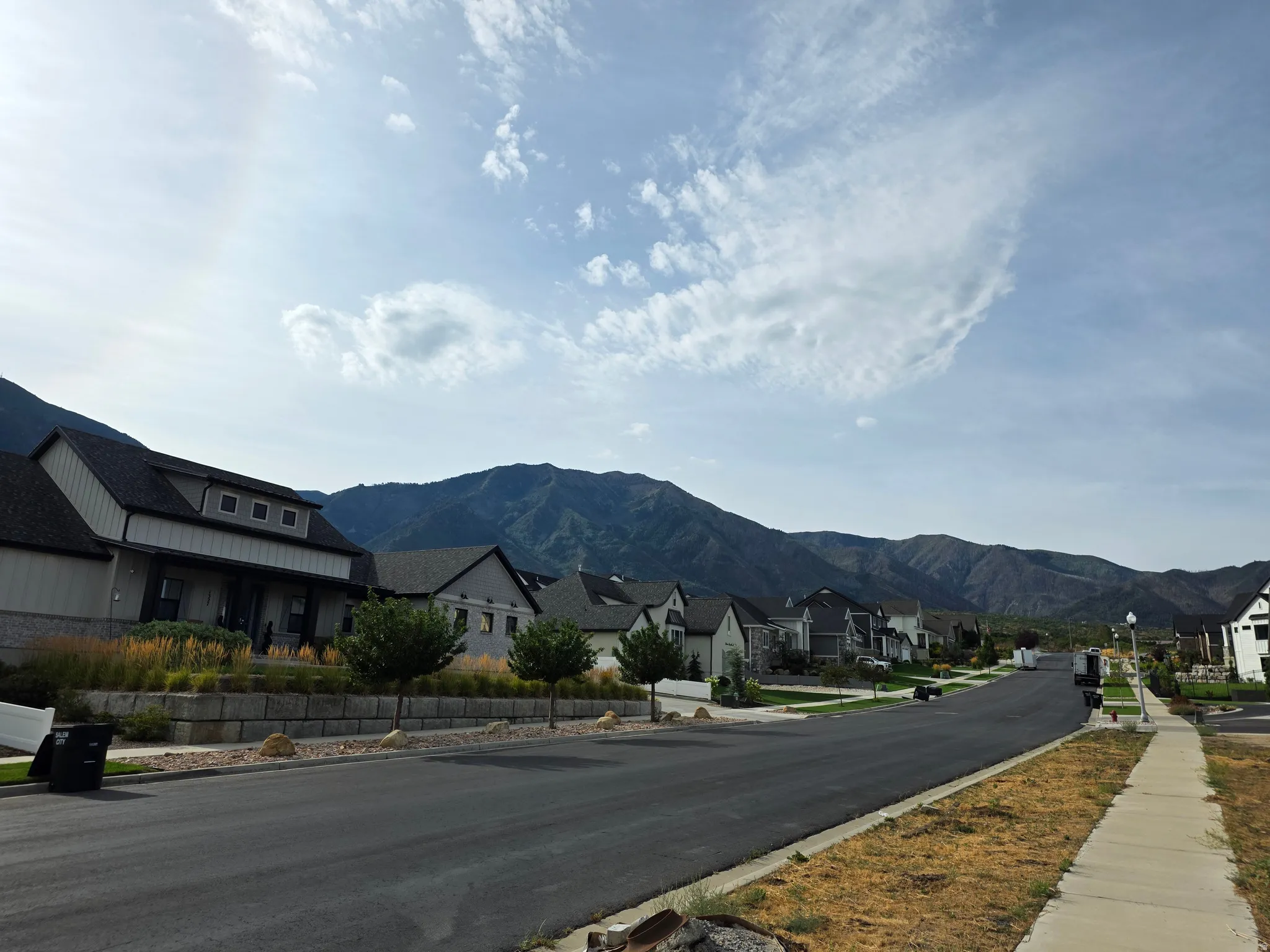 Mountain backdrop with a residential street, featuring a sidewalk and homes