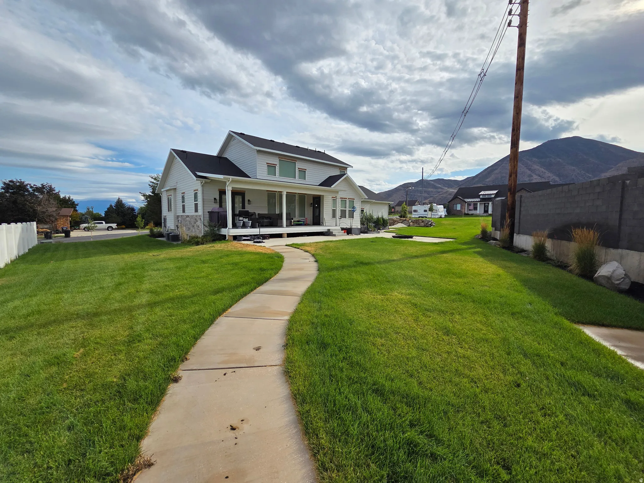 White two-story home with a black roof and stone accent siding