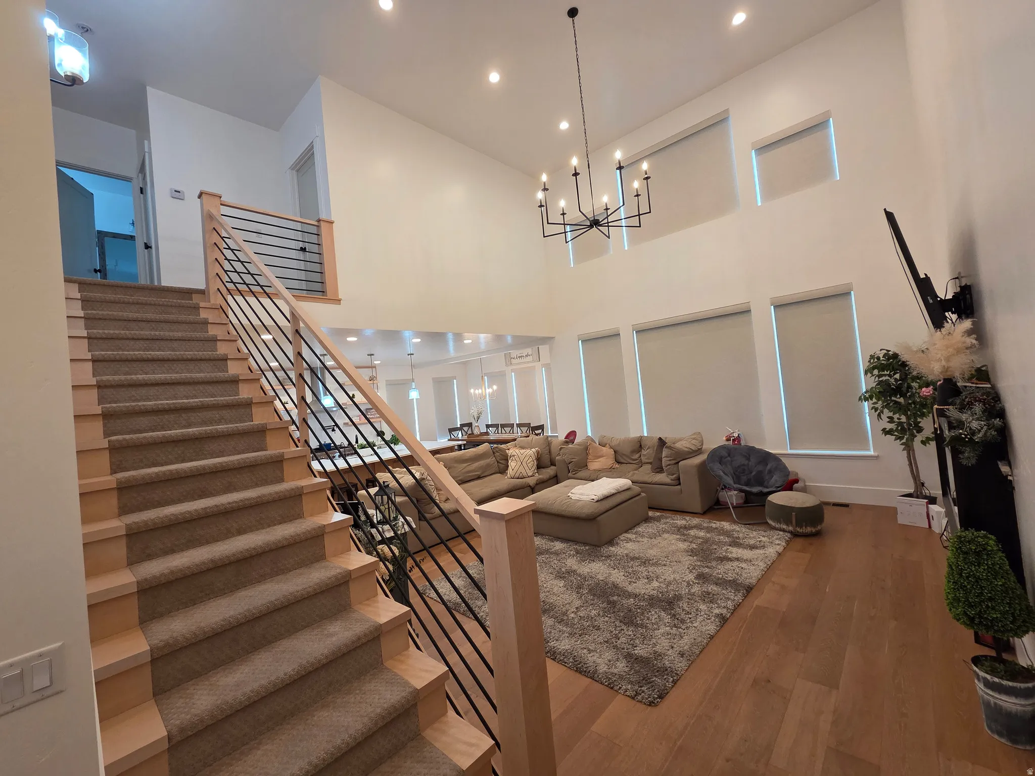 Two-story open-concept living space featuring soaring ceilings, a linear chandelier, and abundant natural light from multiple clerestory windows