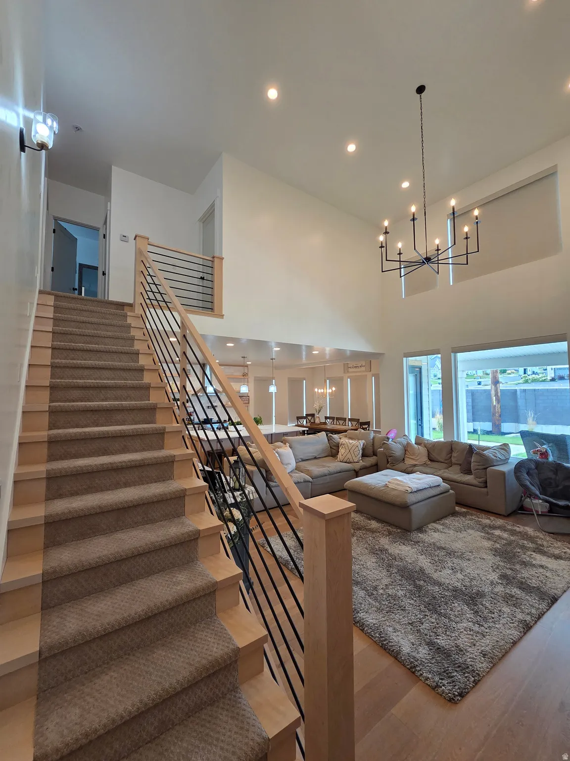 Open-concept living space showcasing soaring ceilings, a modern linear chandelier, and abundant natural light from expansive windows