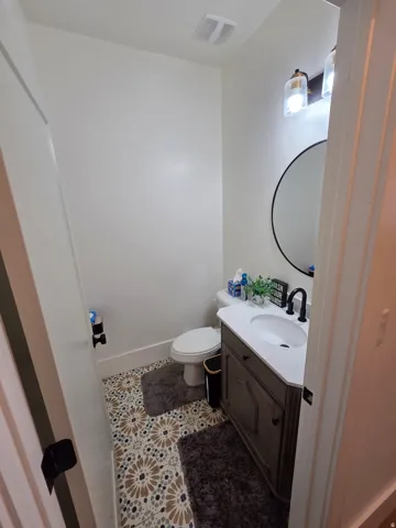 Modern half bath featuring a wood-finish vanity with an integrated rectangular sink, quartz countertop, and matte black faucet