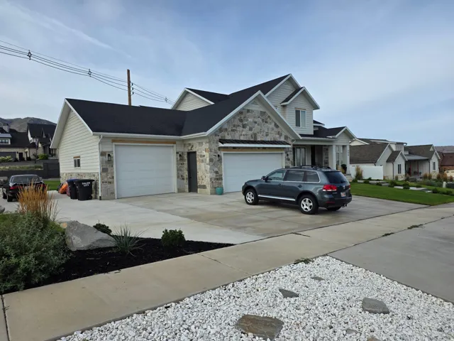 Stone and siding exterior with dark shingle roofing