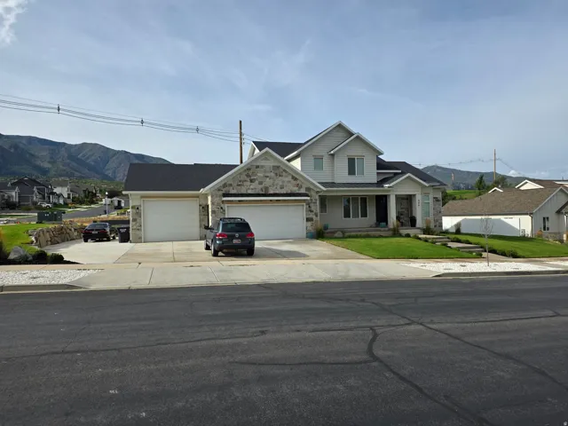 Stone and siding exterior with a multi-car driveway, attached garage, and mountain backdrop
