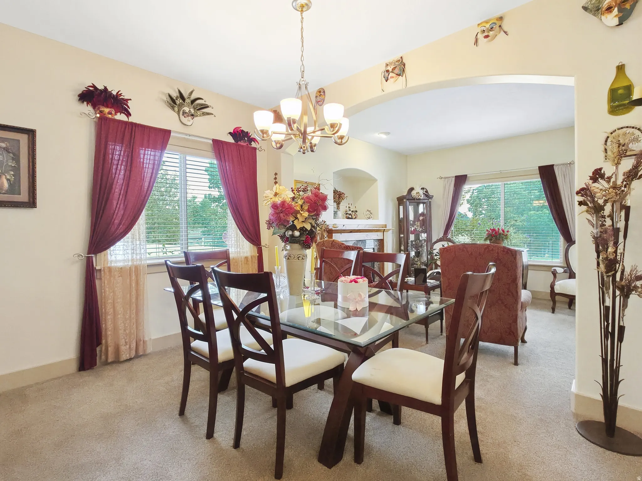 Archway entry to an adjacent room, recessed archway, chandelier lighting fixture, window with blinds, and carpeting