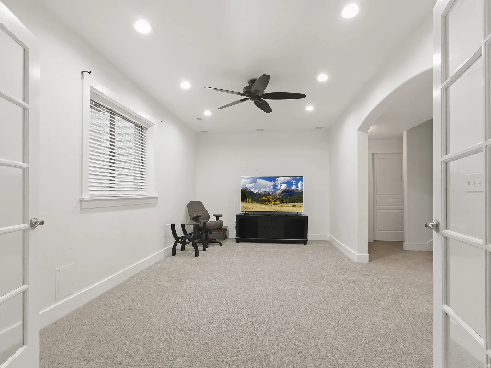 Recessed lighting, ceiling fan, arched doorway, French doors, and light-colored carpeting