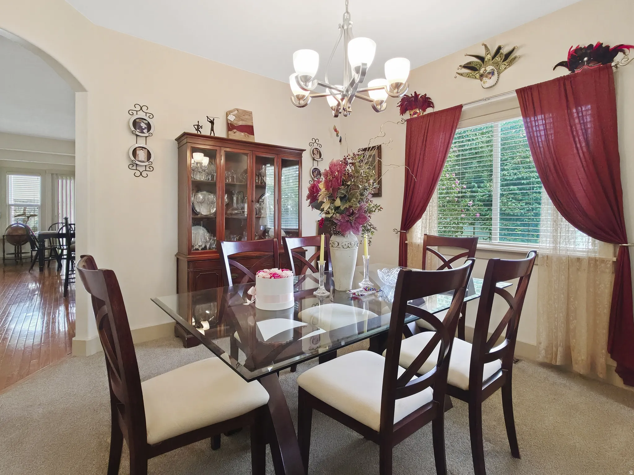 Arched entryway, built-in display cabinet, large window with blinds, and a contemporary chandelier