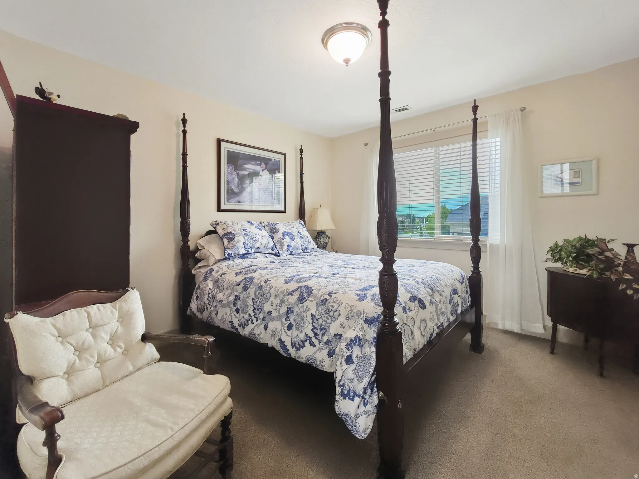 Recessed lighting, wall-to-wall carpeting, and a window with blinds and sheer curtains