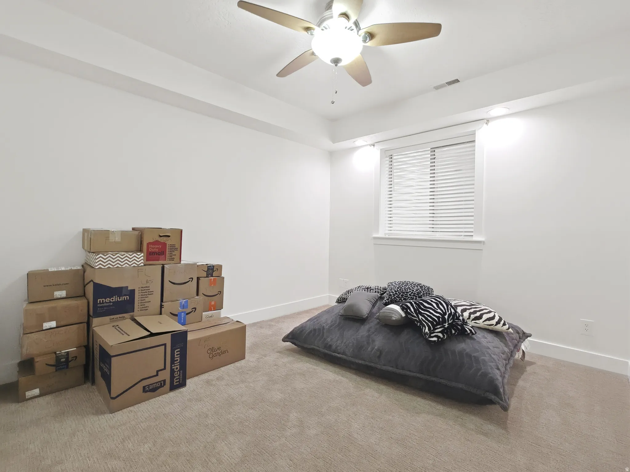 Carpeted room featuring a ceiling fan with integrated lighting, a window with blinds, and white walls