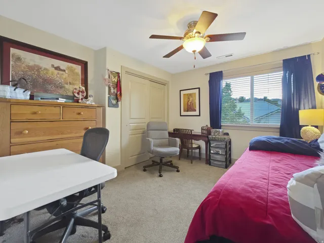 Recessed window with blinds, ceiling fan with integrated lighting, wood-finish sliding closet doors, and neutral carpet flooring