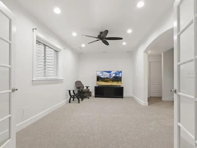 Recessed lighting, ceiling fan, arched doorway, French doors, and light-colored carpeting