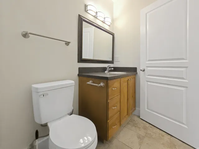 Vanity with wood-finish cabinetry, dark countertop, and integrated sink