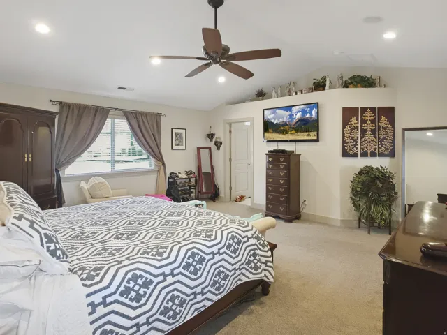 Vaulted ceiling with recessed lighting, ceiling fan, and carpeted flooring