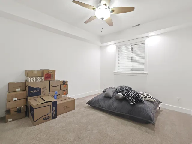Carpeted room featuring a ceiling fan with integrated lighting, a window with blinds, and white walls