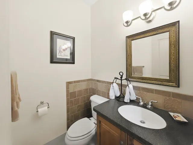 Vanity with dark countertop and oval sink, framed mirror, and three-light vanity fixture