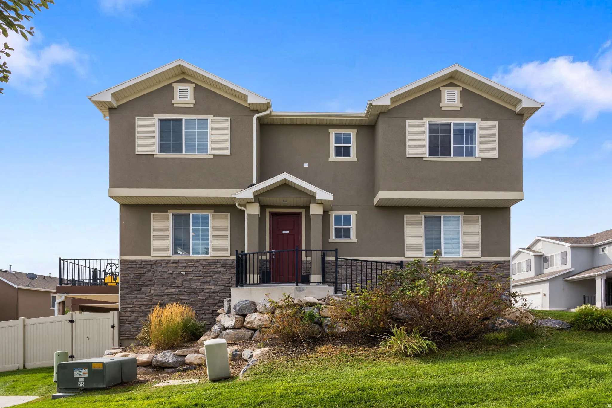 Striking two-story residence featuring a symmetrical facade with dual peaked gables, stone and stucco exterior, and a recessed entry with wrought-iron railings