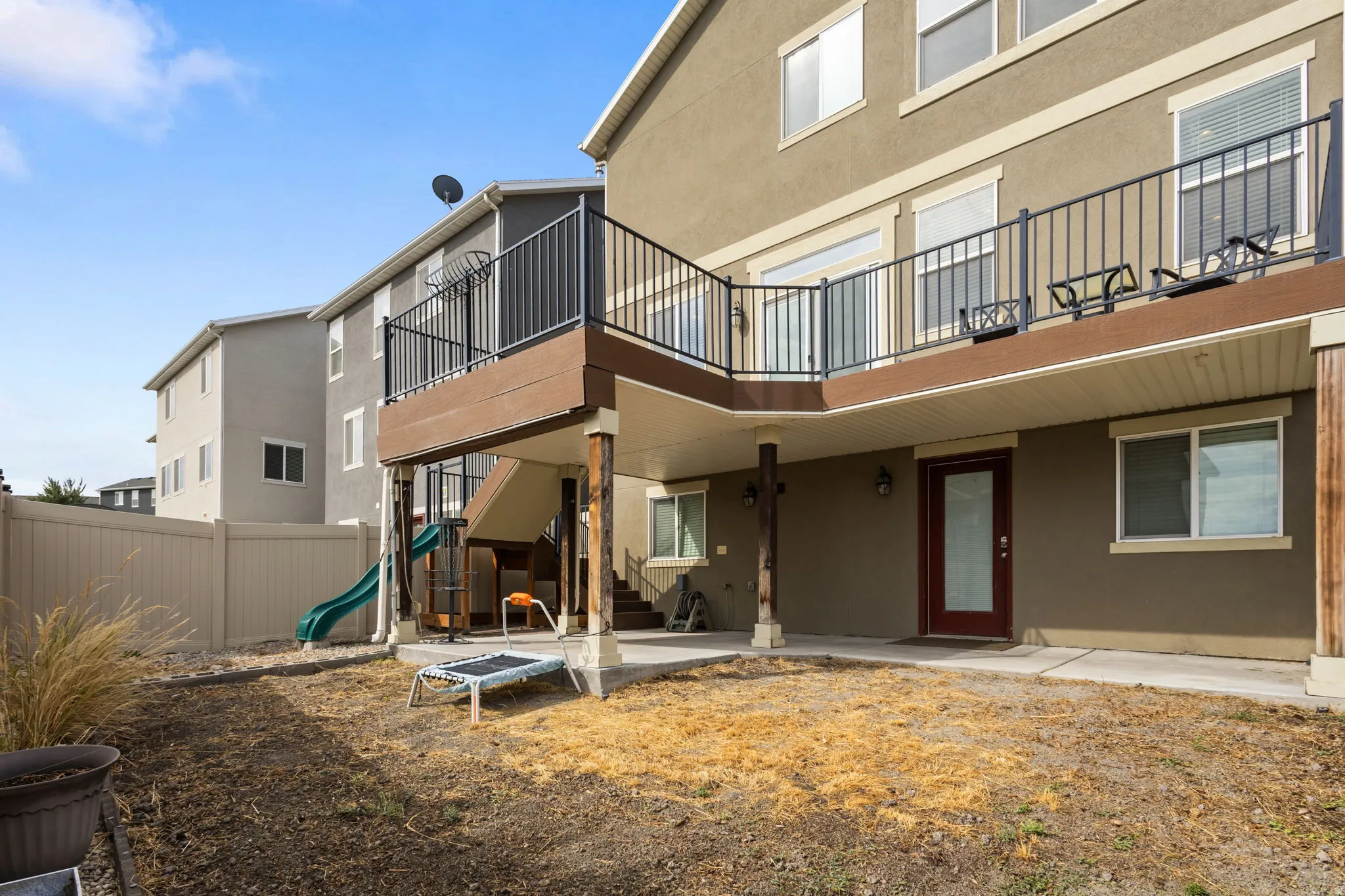 Spacious backyard retreat featuring multi-level composite decking with metal railings, ground-level patio area, and expansive lawn space