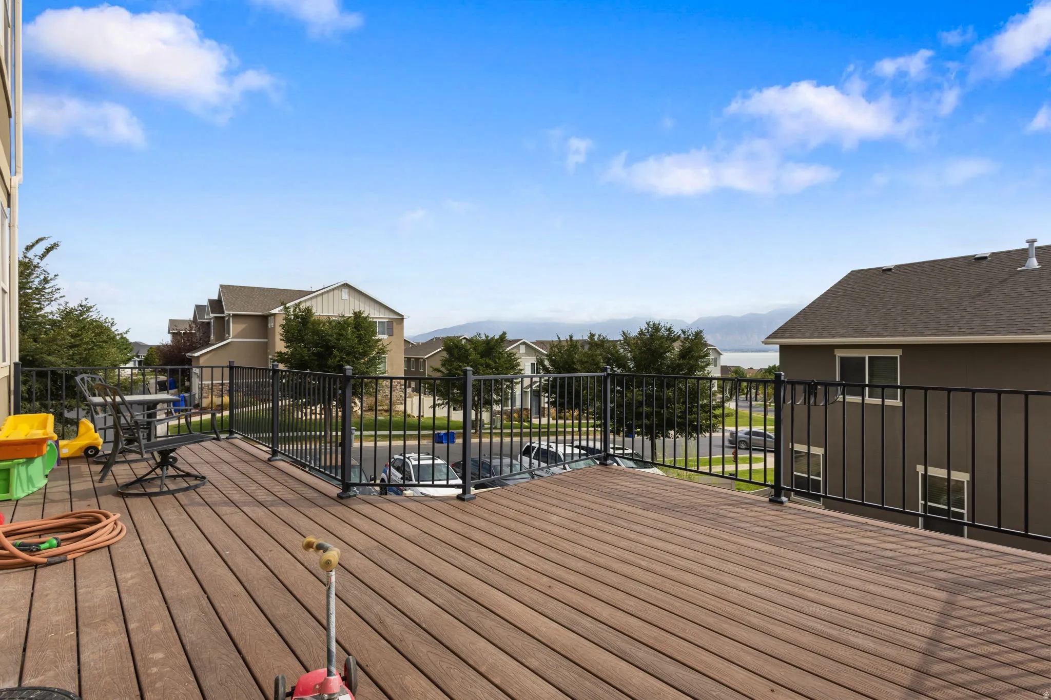 Expansive composite deck with metal railing featuring panoramic sightlines toward distant mountains and surrounding residential properties